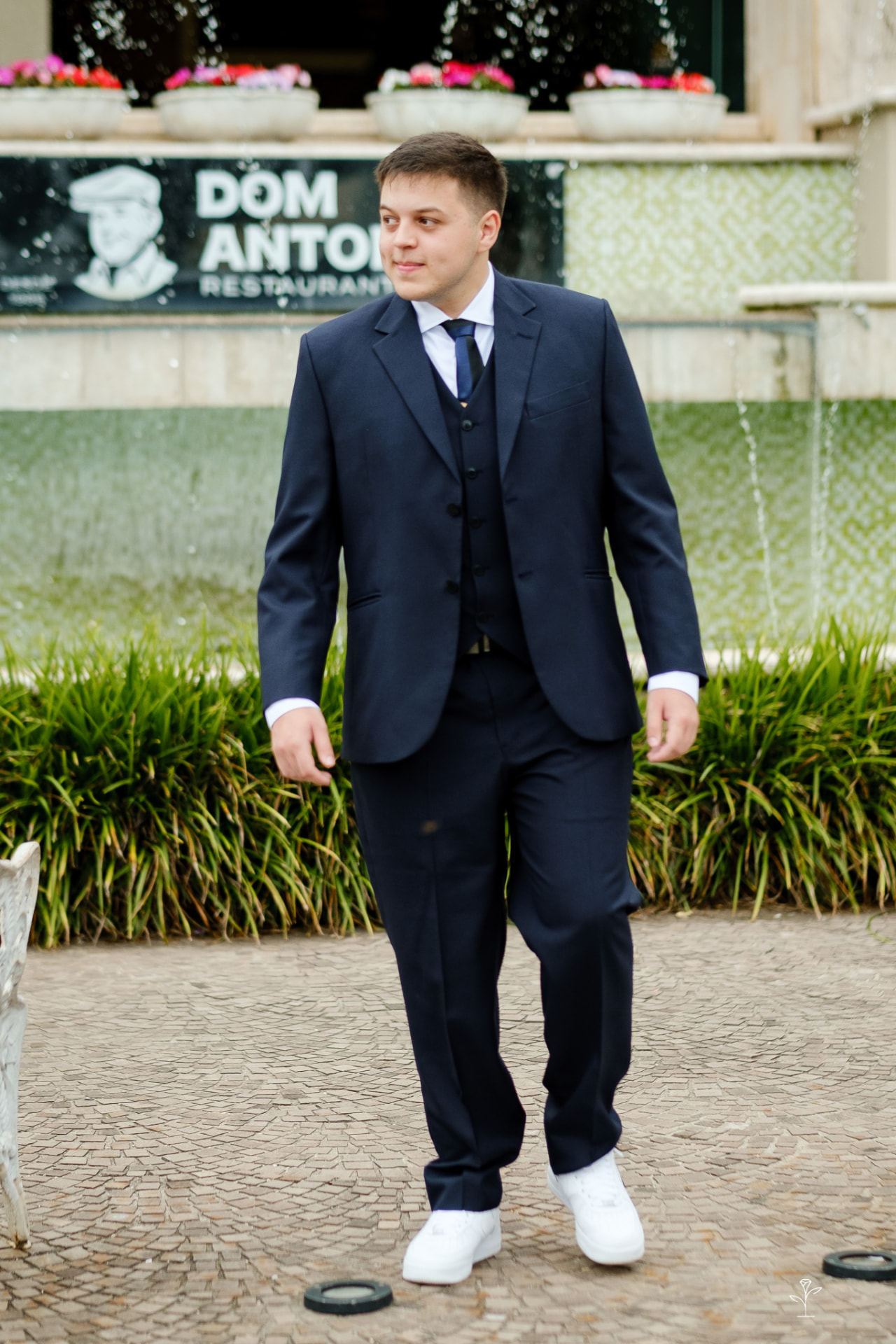 Lucas Desplanches de terno azul, caminhando em uma praça em Curitiba